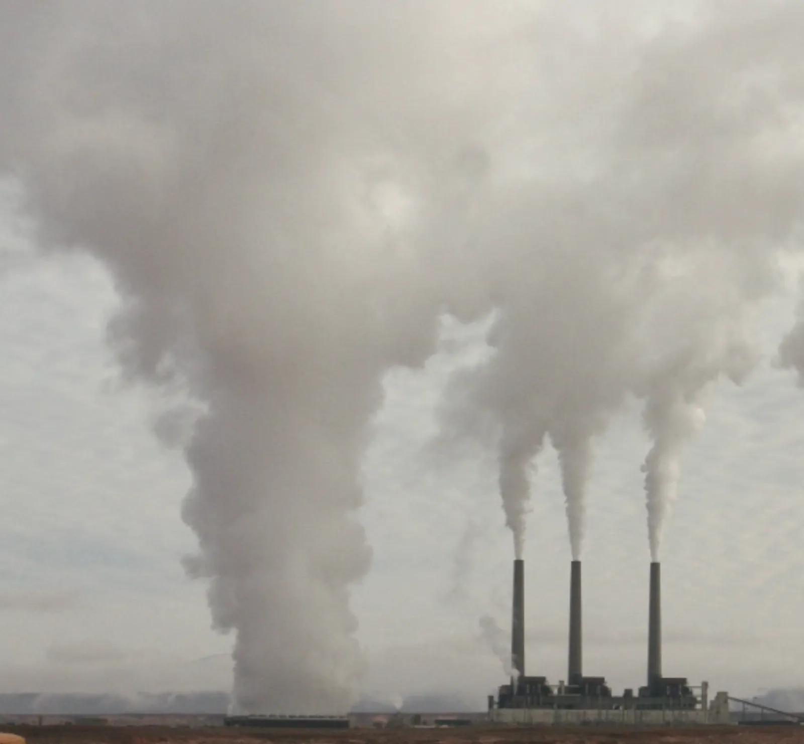 Chimeneas industriales emitiendo grandes columnas de humo, símbolo de las emisiones de gases de efecto invernadero